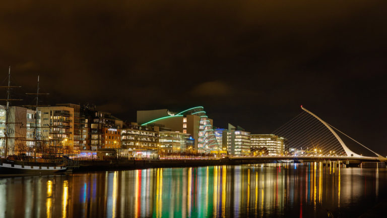 river liffey with building lit up in background at night time