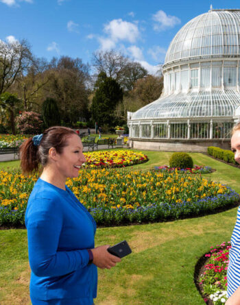 Guests enjoying vibrant gardens and Victorian glasshouse on a sunny day, showcasing hotel's scenic beauty and outdoor amenities.