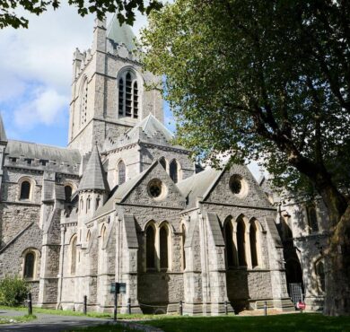 Stunning view of historic cathedral surrounded by lush trees, offering a serene atmosphere near our hotel's prime location.