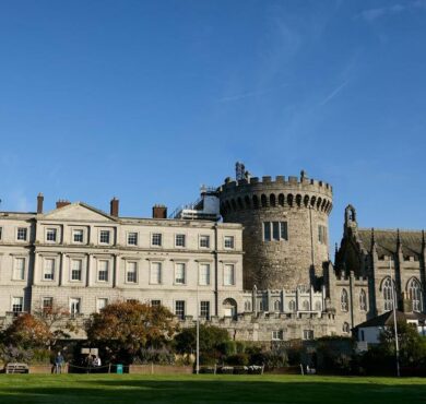 Historic castle hotel exterior with lush gardens under clear blue sky, offering a blend of elegance and heritage.