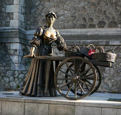 Statue of a woman with a cart, set against stone wall, representing Dublin's historic charm near comfortable hotel stay.