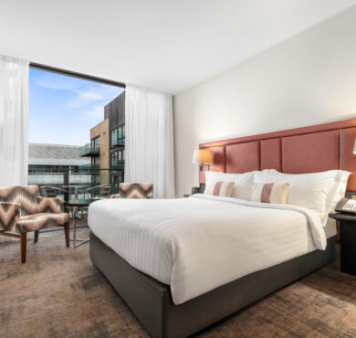 Superior Room featuring a double bed, two chairs with table, work desk, and private balcony — offering a stylish and comfortable stay at The Spencer Hotel.