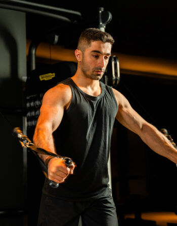 Guest using modern gym equipment in a dimly lit fitness centre, emphasising wellness and strength training.