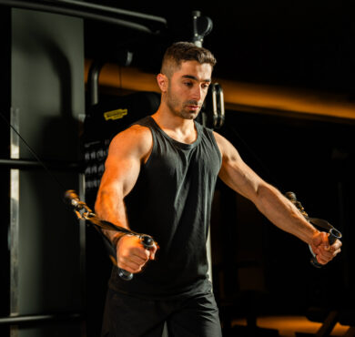 Guest using modern gym equipment in a dimly lit fitness centre, emphasising wellness and strength training.