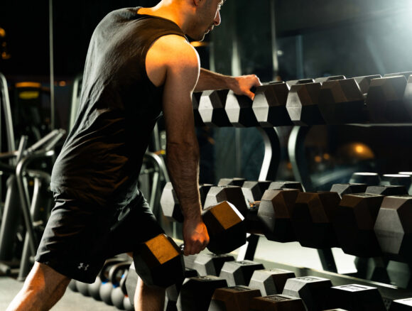 Guest using modern gym with weights, mirrors, and sleek equipment for a quality fitness experience at hotel.