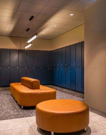 Spacious hotel locker room with modern blue lockers and comfortable tan seating for guests' convenience.