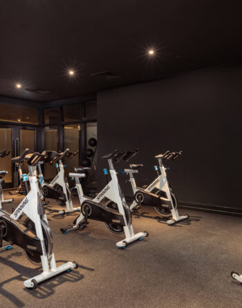 Modern fitness centre with spin bikes under soft lighting, offering a perfect workout environment for hotel guests.