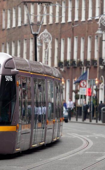 Modern tram passing historic city buildings near hotel, showcasing easy access and vibrant urban surroundings.