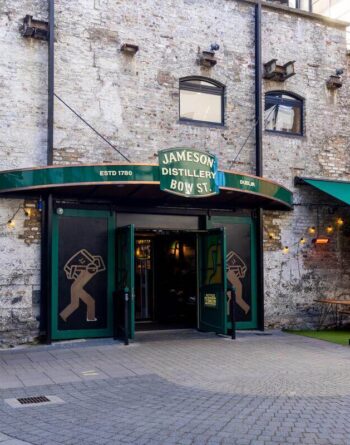 Charming historic brick facade of Dublin hotel with green awnings, inviting entrance, and cosy outdoor seating.
