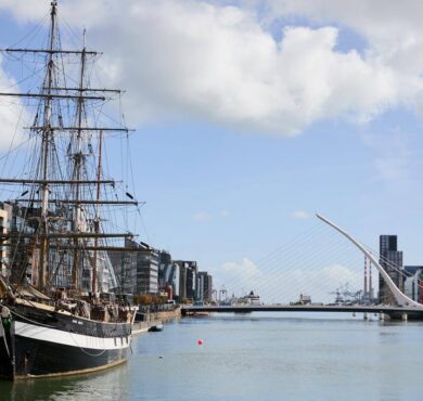 Scenic riverside view of historic ship near modern architecture, perfect for Dublin city explorers.