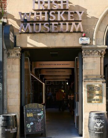 Charming exterior of Irish Whiskey Museum with welcoming signage and nearby pub, highlighting Belfast's cultural allure.