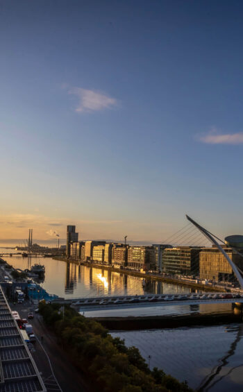 Luxurious hotel rooftop sunset view over river and city skyline, featuring modern architecture and serene ambiance.