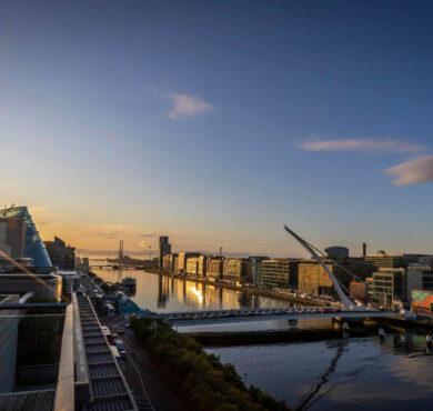 Luxurious hotel rooftop sunset view over river and city skyline, featuring modern architecture and serene ambiance.